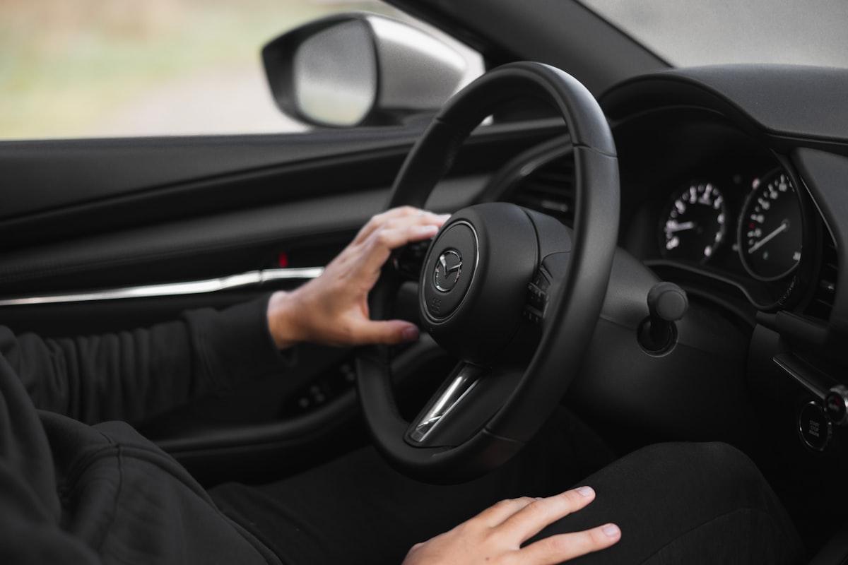 Person kör bil med händerna på ratten inför uppkörning